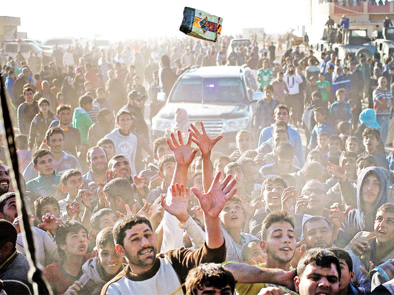 نازحون عراقيون من الموصل يحاولون التقاط مساعدات غذائية توزعها منظمة حكومية قرب الموصل أمس       (رويترز)