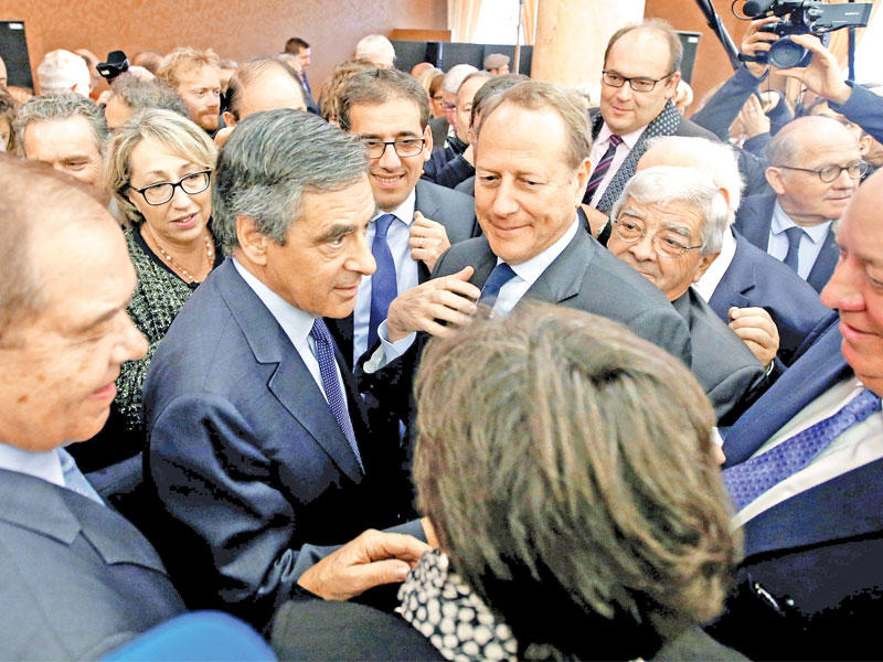 فيون محاطاً بنواب خلال اجتماع في باريس أمس (أ ف ب)