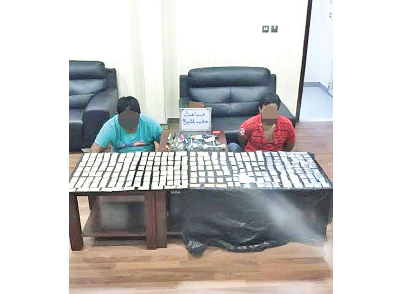 المتهمان وأمامهما المضبوطات