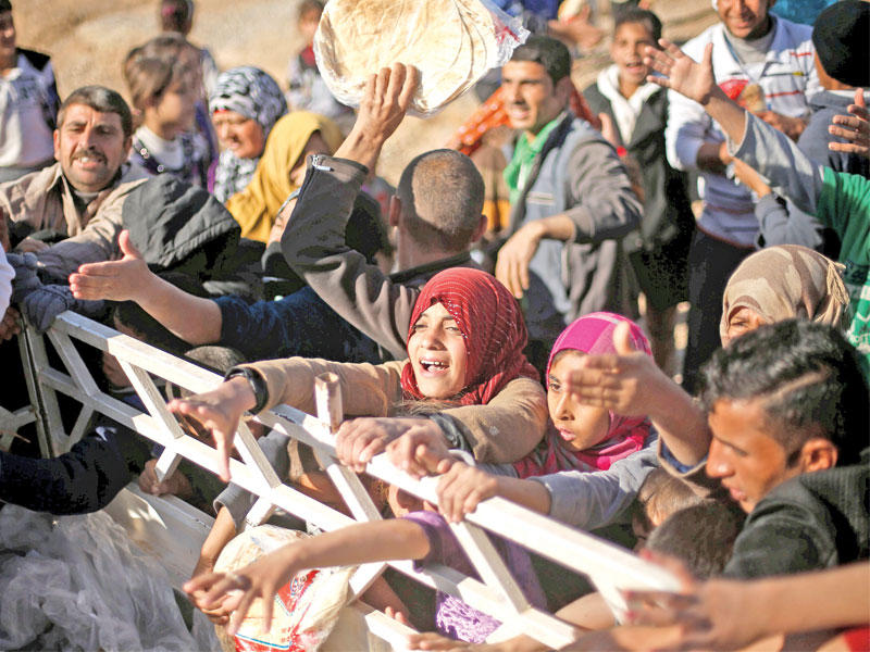 نازحون عراقيون يحصلون على مساعدات في مخيم الخازر (رويترز)