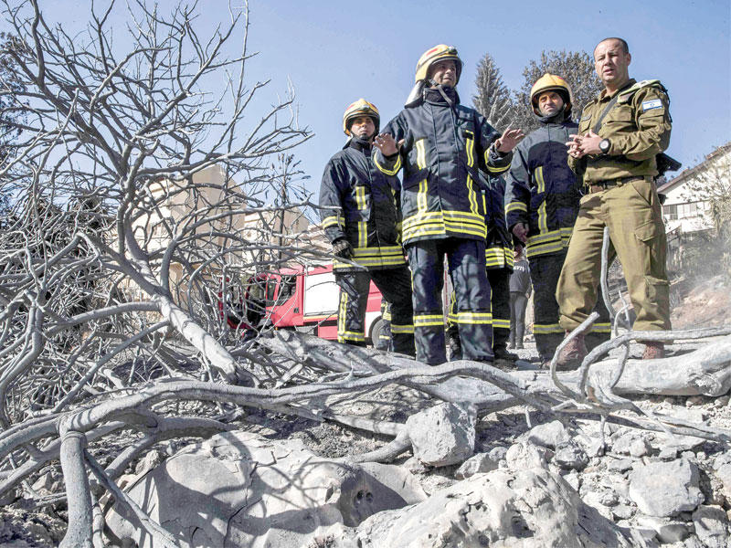 ضابط إسرائيلي يعرف طاقم إطفاء فلسطينياً على منطقة عمله في حيفا أمسt(أ ف ب)