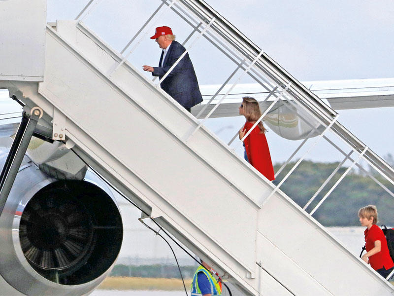 ترامب وزوجته ميلانيا وابنه بارون في طريقهم إلى الطائرة التي تقلهم من فلوريدا حيث قضوا إجازة عيد الشكر إلى نيويوركt (رويترز)