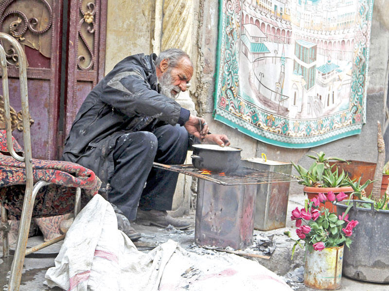 حلبي مسن يحضر غداءه خارج منزله المدمر باستخدام الحطب في 22 يناير 2016       (رويترز)