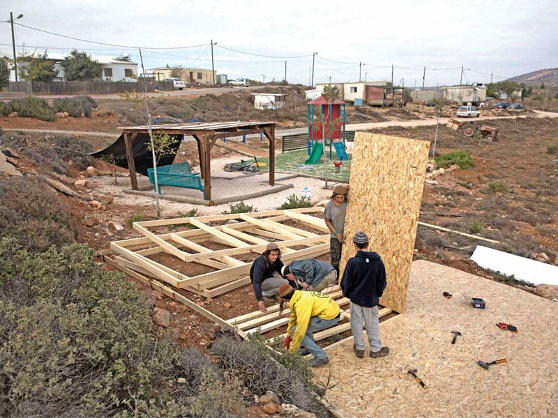 شبان من المستوطنين اليهود يبنون أمس منزلاً في قطعة أرض فلسطينية في الضفة الغربية خارج مستوطنة عمونا كانت تضم مستوطنة عشوائية أمرت المحكمة الإسرائيلية العليا بإزالتها (أ ف ب)