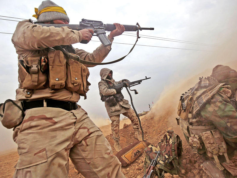 عناصر من الحشد الشعبي تقاتل رغم رداءة الجو في تل عبدة جنوب تلعفر أمس (أ ف ب)