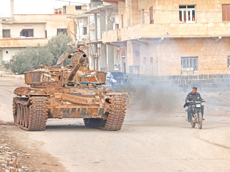 سوري يتجاوز بدراجته البخارية دبابة لفصائل المعارضة في أحد شوارع درعا أمس  (أ ف ب)