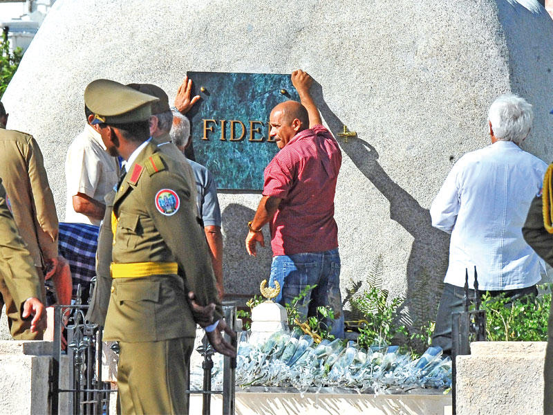 موظفون يثبتون لوحة على ضريح كاسترو في سانتياغو أمس (أ ف ب)