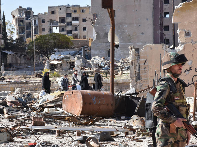 جندي من النظام ومن خلفه مجموعة من المدنيين في حلب