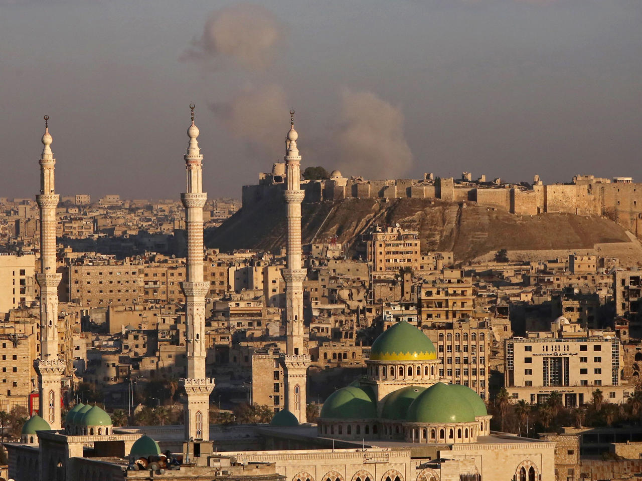 الدخان يتصاعد بالقرب من القلعة التاريخية في حلب القديمة خلال معارك بين قوات النظام السوري والمقاتلين