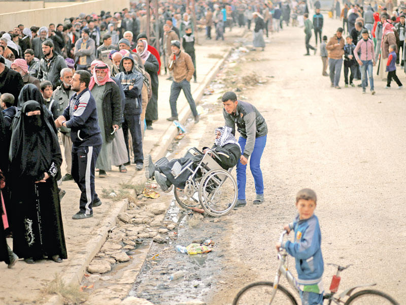 عراقيون في انتظار الحصول على مساعدات خارج نقطة توزيع تديرها الأمم المتحدة في حي الزهراء شرق الموصل أمسt(رويترز)