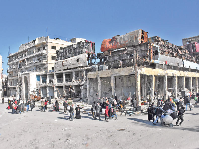 سوريون عائدون إلى حي باب الحديد في حلب الشرقية أمس (أ ف ب)