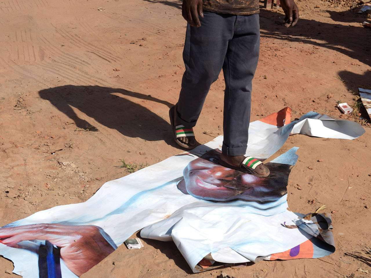 رجل يسير على ملصق انتخابي للرئيس المنتهية ولايته غامبيا يحيى جامع