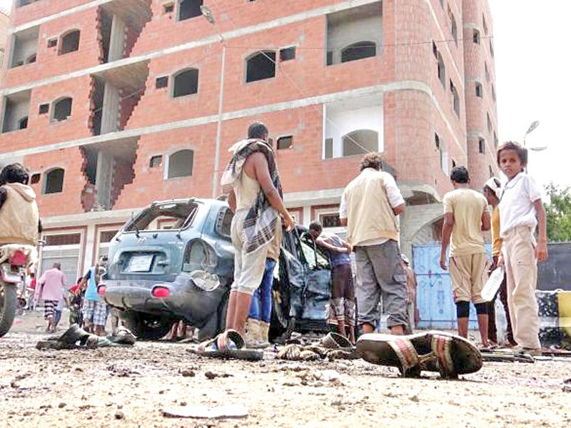 يمنيون أمام بوابة المعسكر الذي استهدف في حي خور مكسر بعدن أمس (شبكة بويمن)