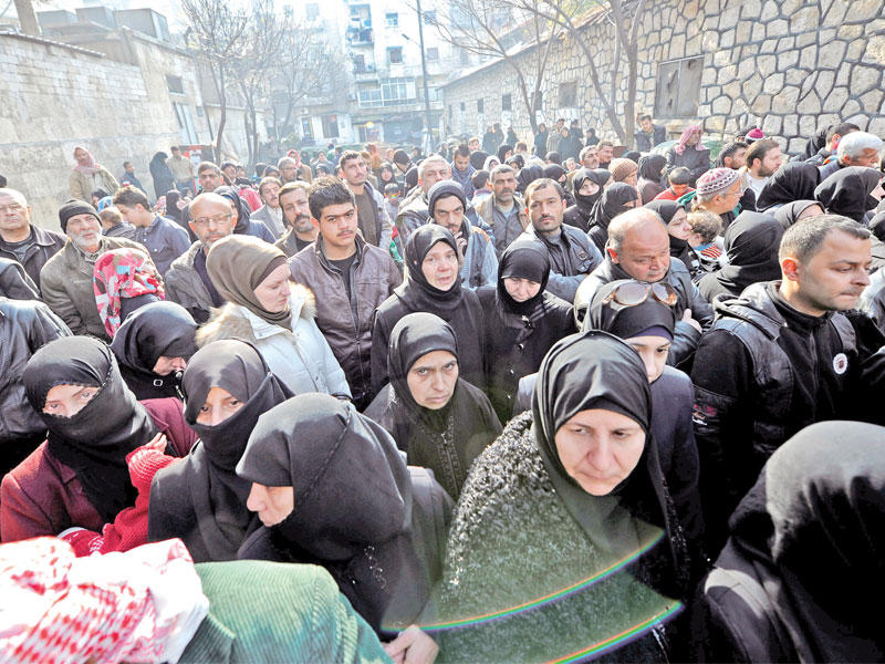 سوريون يتكدسون أمام حاجز لقوات النظام للخروج من حلب الشرقية أمس      (رويترز)