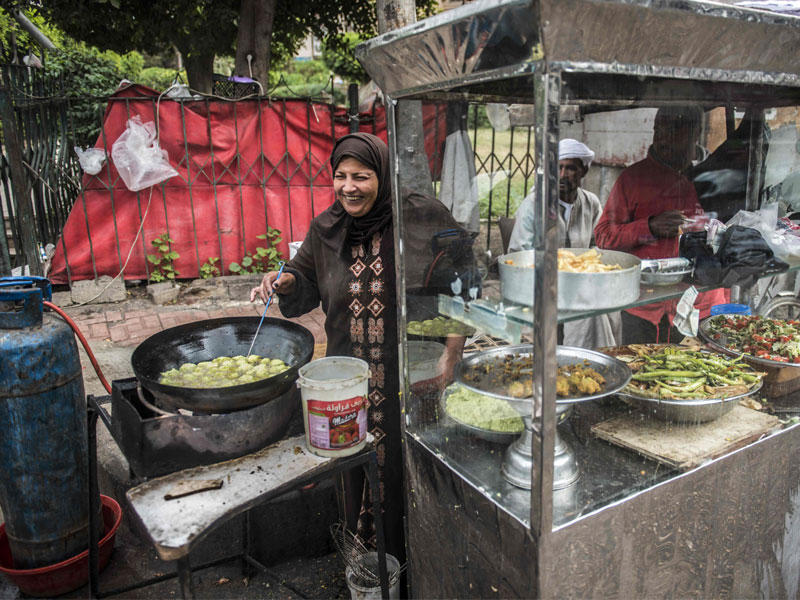 سيدة مصرية تحضر أطعمة على عربة بوسط القاهرة أمس (أ ف ب)