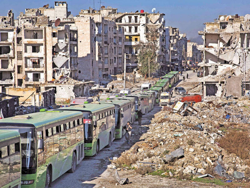 قافلة الحافلات المخصصة لإجلاء المسلحين والمدنيين في شرق حلب أمس (أ ف ب)