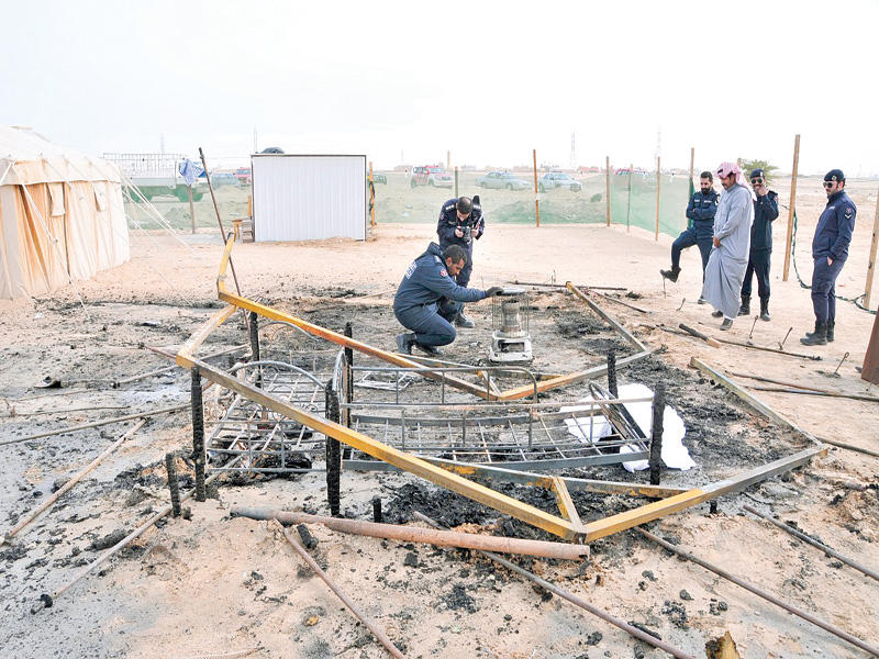 رجال الإطفاء والأدلة الجنائية يعاينون آثار حريق أحد المخيمات