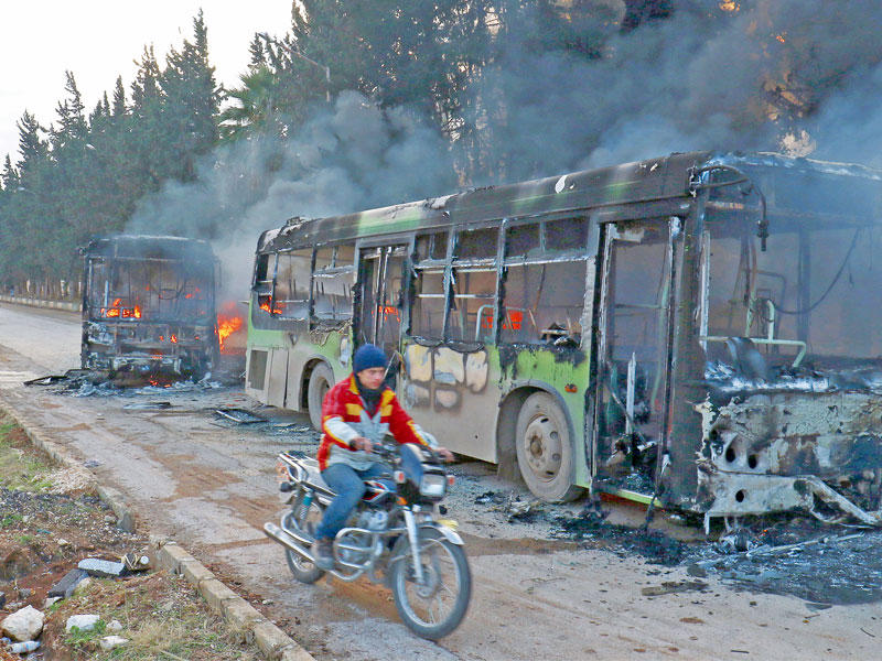 حافلتان مخصصتان لإجلاء مدنيين من قريتي الفوعا وكفريا في إدلب تحترقان أمس (رويترز)