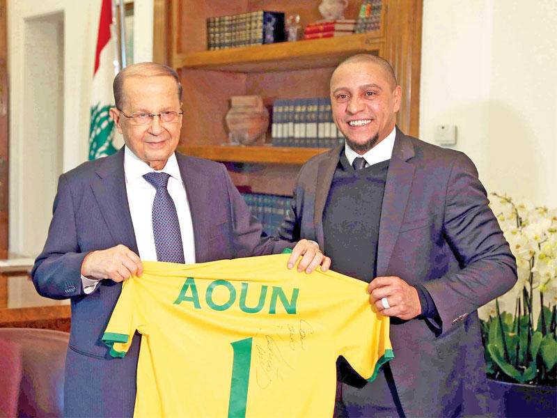 عون يتسلم قميصاً باسمه من نجم كرة القدم البرازيلي روبرتو كارلوس في بعبدا أمس (إي بي إيه)