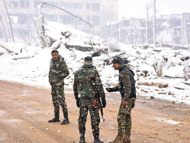 جنود للنظام على طريق تغطيه الثلوج في حلب أمس        (أ ف ب)