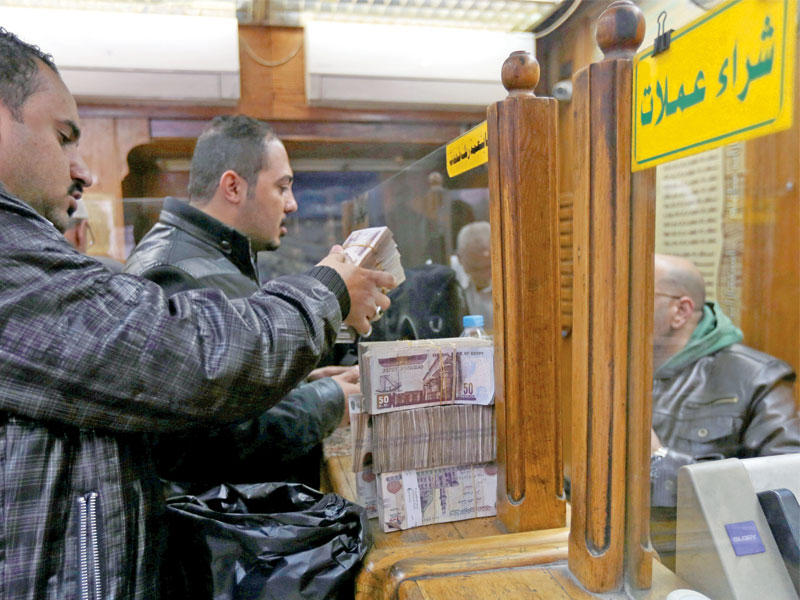 مصريون يغيرون الدولار بالعملة المصرية في محل للصرافة وسط القاهرة أمس (رويترز) 