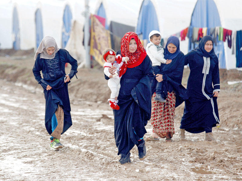 مهجرات عراقيات يسرن بصعوبة وسط الوحل في أحد الشوارع قرب الموصل أمس      (رويترز) 