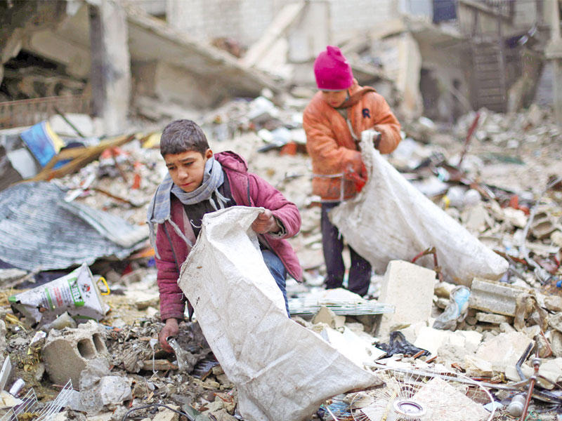 صبيان سوريان يجمعان الحطب من بين الأنقاض لاستخدامه في التدفئة والطهي في ضاحية زملكا قرب دمشق أمس (أ ف ب)