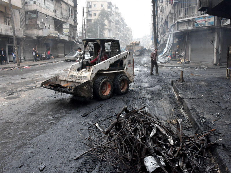 جرار يزيل الأنقاض كما تبدأ الحكومة السورية لتنظيف المناطق التي يسيطر عليها سابقا من قبل قوى المعارضة في مدينة حلب