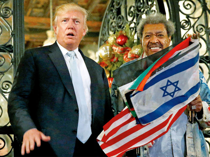 ترامب متحدثا للصحافيين وبجواره أحد أنصاره أمام مقر إقامته في بالم بيتش بفلوريدا أمس الأول    (رويترز)