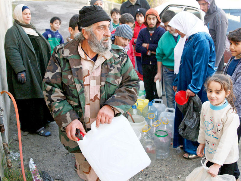 جندي مسن يزاحم الأهالي على المياه في دمشق أمس (إي بي أيه)