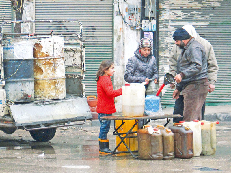 طفلة سورية تشتري البنزين مع أخيها شمال إدلب أمس (أ ف ب)