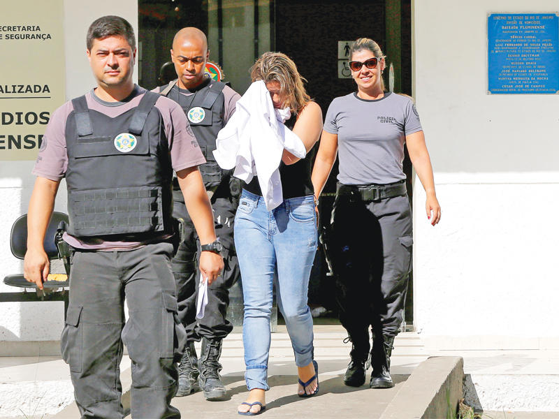 زوجة السفير تغطي وجهها برفقة الشرطة البرازيلية أمس (رويترز)n