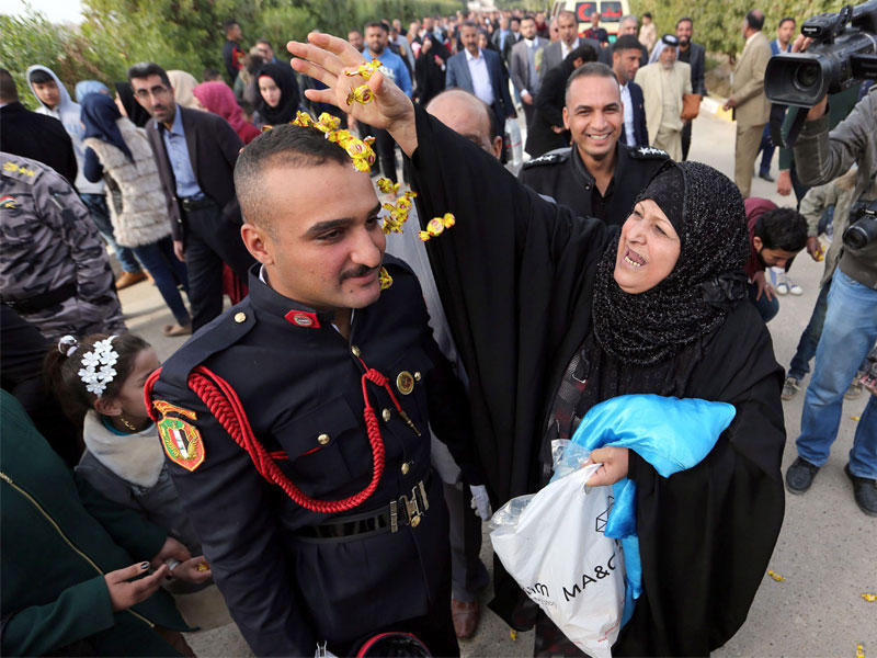 عراقية تنثر الورد على ابنها خلال تخرجه في الأكاديمية العسكرية ببغداد أمس (إي بي أيه)