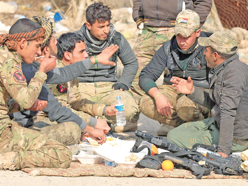 عناصر من القوات العراقية المشتركة خلال استراحة بحي سومر شرق الموصل أمس (رويترز)