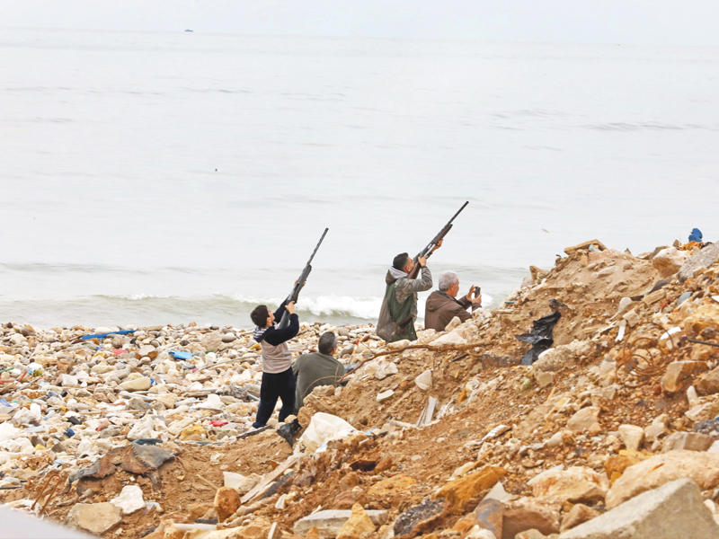 في الصورة صياديون يصوبون على الطيور قرب المطار أمس (أ ف ب)