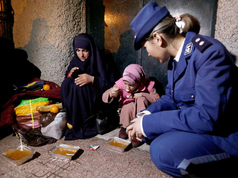 شرطية جزائرية تشرف على تناول أسرة بلا مأوى وجبة غذائية في العاصمة يوم الأربعاء (رويترز)