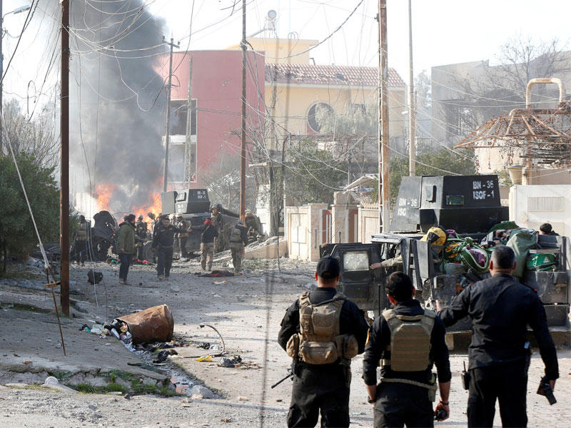 عناصر من عمليات مكافحة الإرهاب يتابعون احتراق سيارة لداعش في حي الأندلس بالموصل أمس (رويترز)