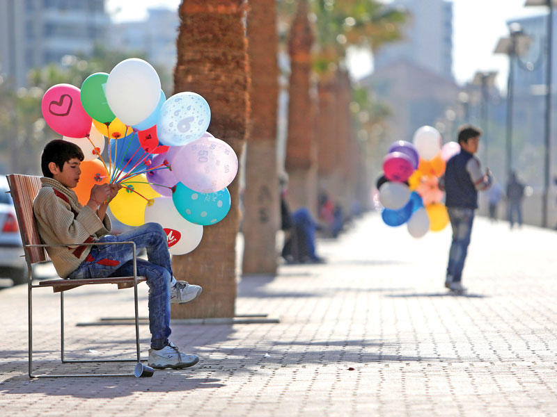 فتيان سوريان يبيعان البالونات على كورنيش صيدا (رويترز)