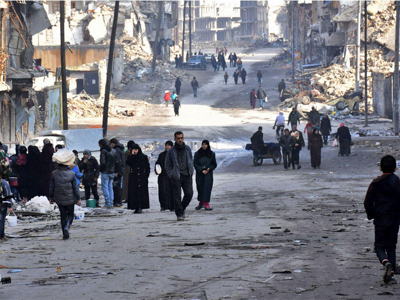 سوريون في أحد شوارع حي طريق الباب المدمر بحلب أمس الأول  (أ ف ب)