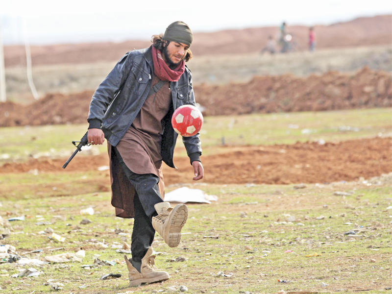مقاتل سوري يلعب الكرة ممسكاً بسلاحه في بلدة الراعي بريف حلب أمس الأول                      (رويترز)