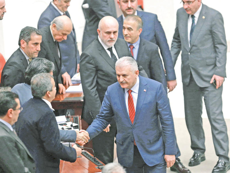 يلدريم مصافحاً نواب حزب الشعوب الكردي بعد إقرار التعديلات الدستورية داخل البرلمان بأنقرة أمس (أ ف ب)