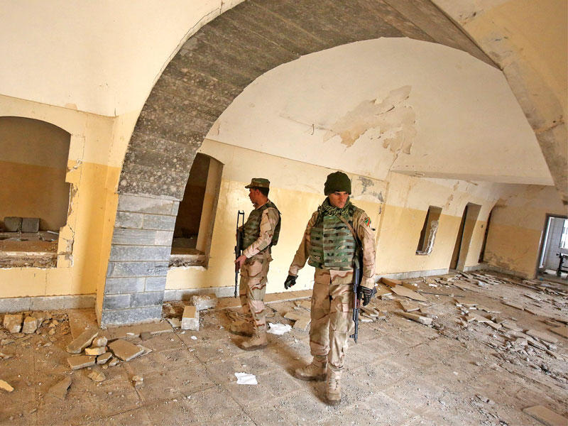 عناصر من القوات العراقية يتفقدون كنيسة مار جرجس في الموصل بعد تدمير تنظيم «داعش» لها أمس  (أ ف ب)