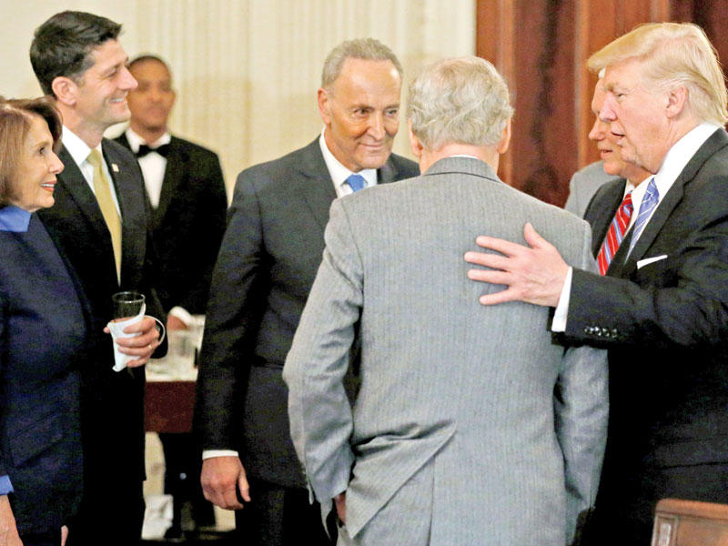 ترامب واضعاً ذراعه حول زعيم الأغلبية في الكونغرس الجمهوري ميتش ماكونيل خلال حفل استقبال لقادة ديمقراطيين وجمهوريين في البيت الأبيض أمس الأول (رويترز)