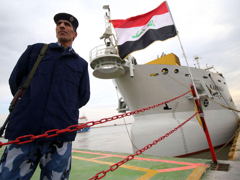 شرطي عراقي يقف أمام سفينة في معرض تجاري عند ميناء أبو فلوس في البصرة أمس  (أ ف ب)