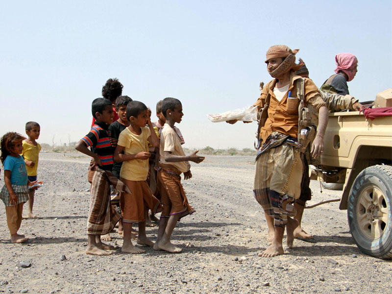 مقاتلون موالون للحكومة يقدمون المعونات الغذائية للأطفال اليمنيين