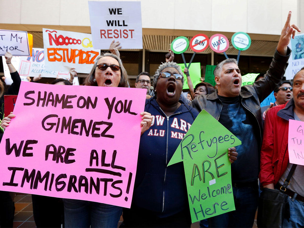 المتظاهرون يصرخون ويرفعون لافتات أثناء مظاهرة ضد عمدة كارلوس خيمينيز والرئيس الأمريكي دونالد ترامب