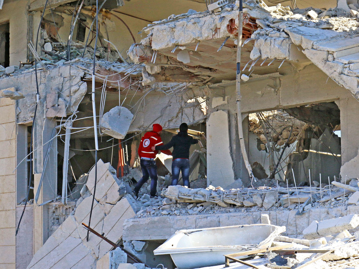 عناصر من «الهلال الأحمر السوري»  في مبنى تعرض لغارة في إدلب أمس      (رويترز)