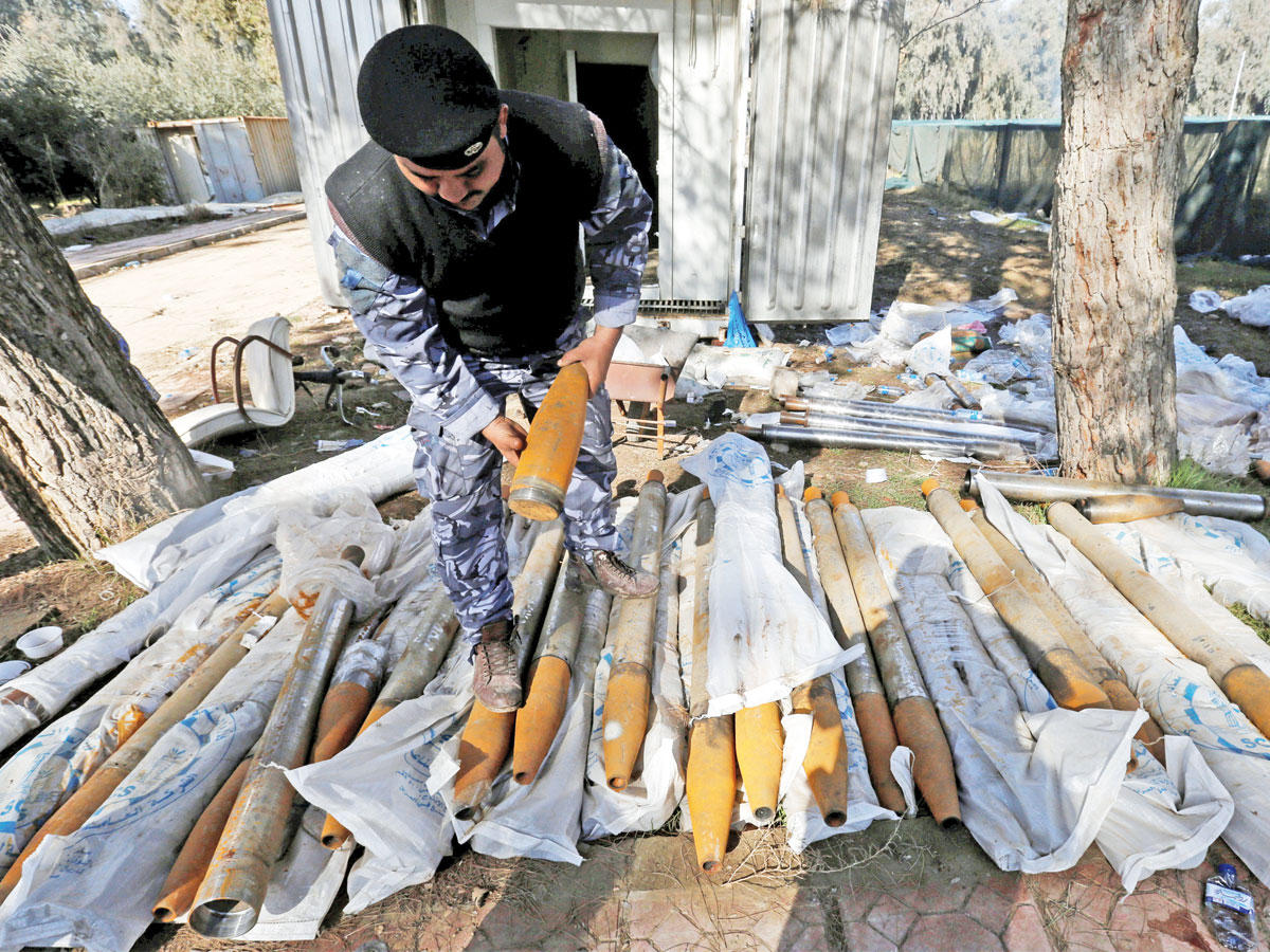 عسكري عراقي يتفقد مجموعة من الصواريخ الجديدة التي عثر عليها في مخبأ لـ «داعش» في الموصل أمس   (رويترز)