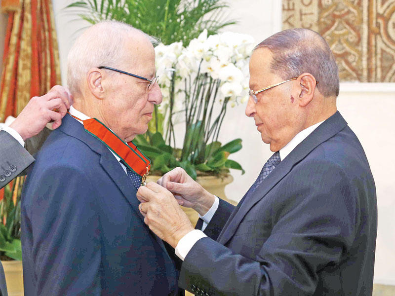 الرئيس عون مقلداً وسام الأرز الوطني للفنان إيلي شويري (رويترز)