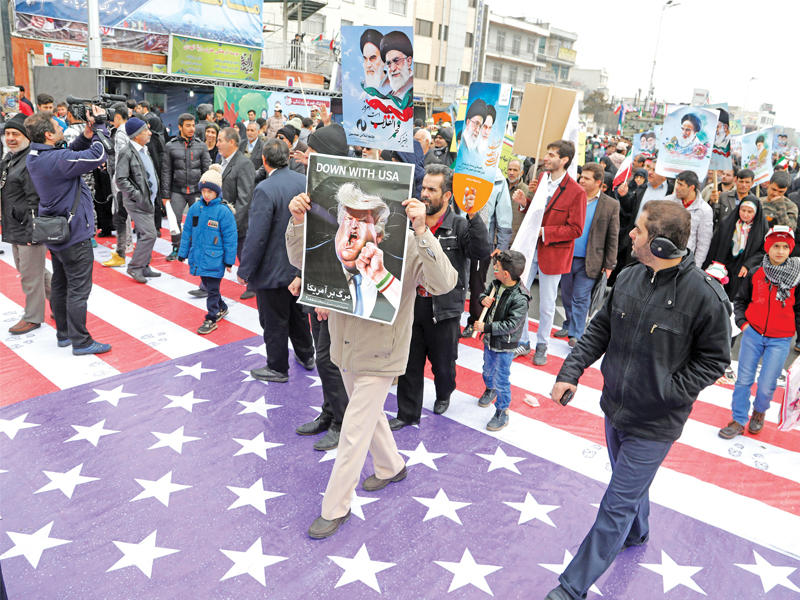 إيرانيون يدوسون علماً أميركياً في ساحة «آزادي» وسط طهران أمس الأول خلال إحياء الذكرى 38 للثورة (إي بي أيه)